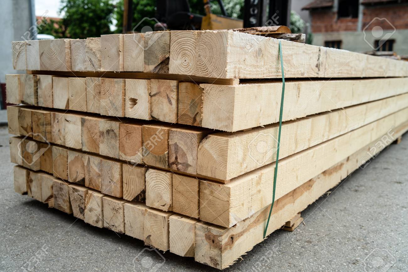 Stack of rough sawn timber pine lumber construction material at the building site warehouse